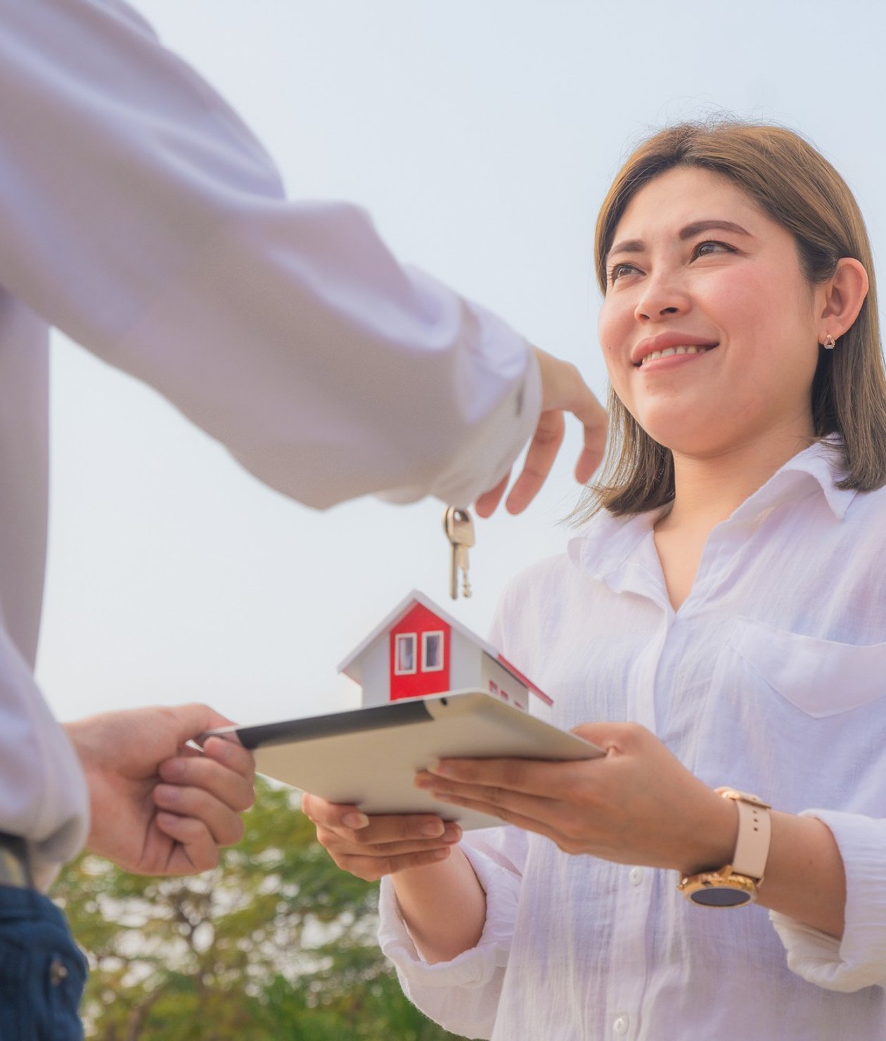 a woman trading a model of a house for a set of keys