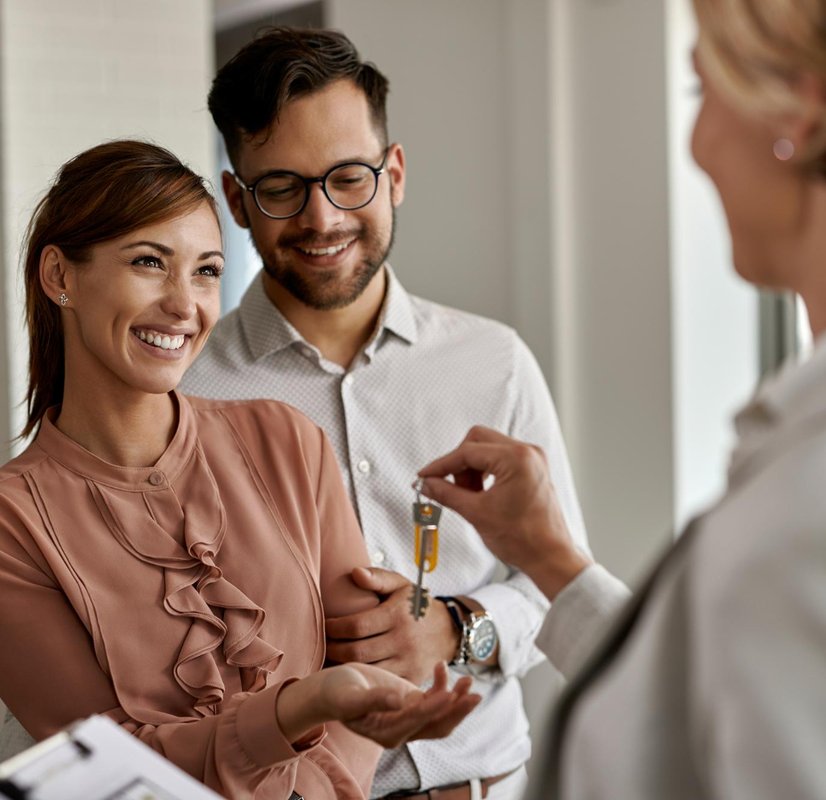 a mortgage broker and a happy couple exchanging keys